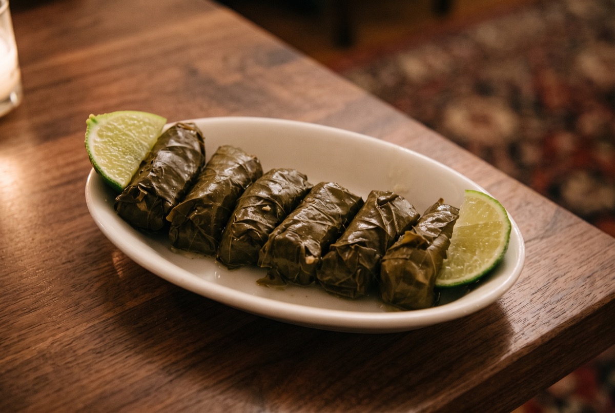 Dolmeh (Veggie) · Grape leaves hand-rolled and stuffed with seasoned rice, herbs, and split peas, slow-simmered until tender,…